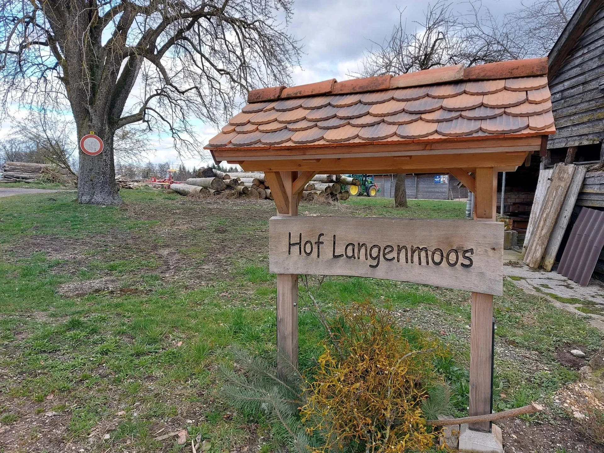 Holzschild mit der Aufschrift Hof Langenmoos am Hofeingang